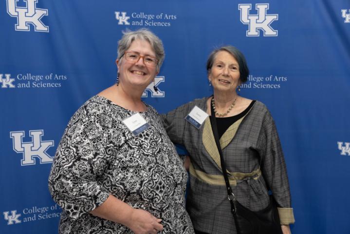 Two attendees pose in front of a backdrop